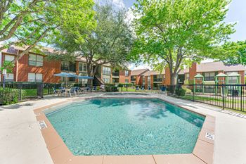 A swimming pool surrounded by trees and a fence.